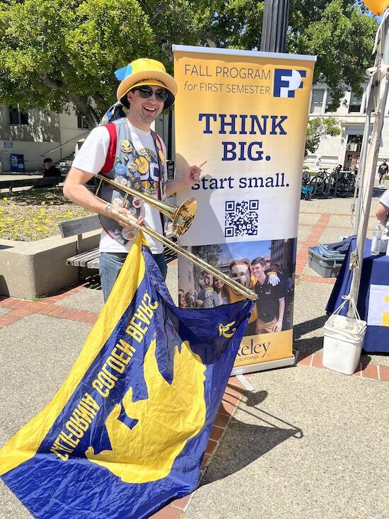 Student at Cal Day in front of sign that says "Fall Program for First Semester. THINK BIG. Start small."